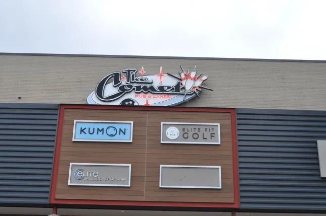 Exterior sign for The Comet Pub & Lanes above storefronts for Kumon, Elite Fit Golf, and Elite Radiology of Georgia.