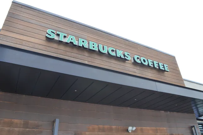 Exterior of a Starbucks Coffee shop with the storefront sign on a wood-paneled building