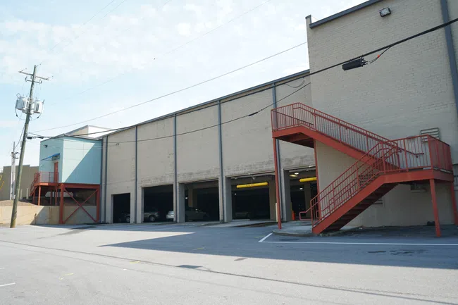 Urban commercial building with multiple garage bays and red exterior staircases under clear sky.
