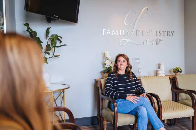 Woman sitting in a dental office waiting area with Family Law Dentistry sign visible on wall.