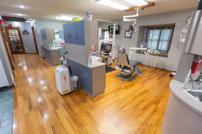 Modern dental clinic interior with dental chair, equipment, wooden floor, and cabinets in a clean environment