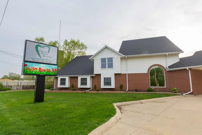 Exterior view of Ortreven Dental Associates building with green lawn and large signage on a cloudy day