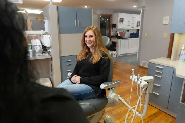 Smiling woman sitting in a dental chair in a modern dental office during a consultation.