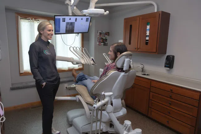 Dentist talking to a relaxed patient seated in a dental chair during a consultation in a modern dental office.