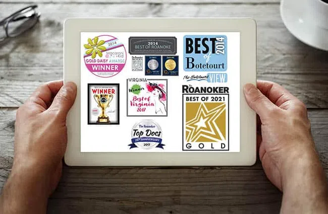 Tablet screen displaying multiple award badges including Best of Roanoke and Gold Daisy Awards from 2014 to 2021.