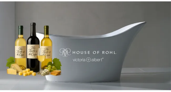 Modern gray freestanding bathtub with wine bottles, cheeses, grapes, and crackers for a luxury lifestyle scene