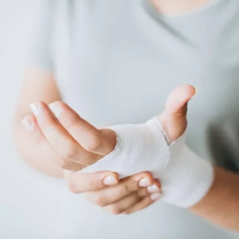 Close-up of a person's hand wrapped in white gauze bandage indicating injury or healing process.