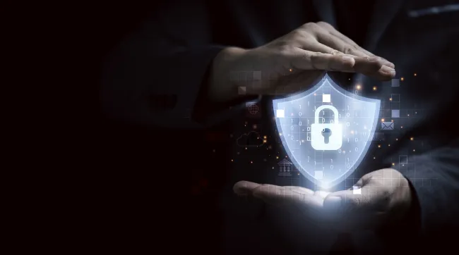 Hands protect glowing shield with padlock symbolizing cybersecurity and data protection