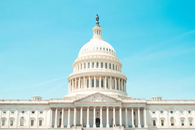 United States Capitol building under a clear blue sky with prominent dome and columns.