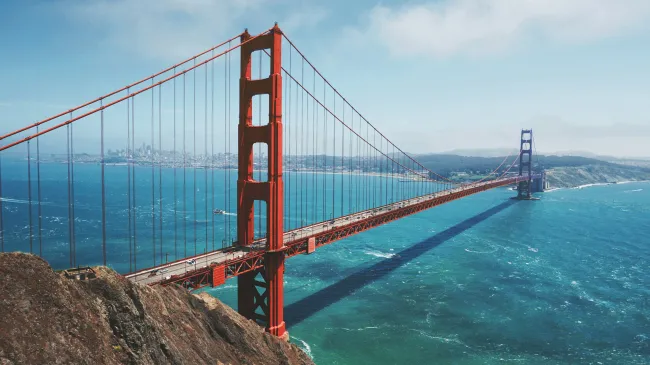 a large red bridge over water with Golden Gate Bridge in the background