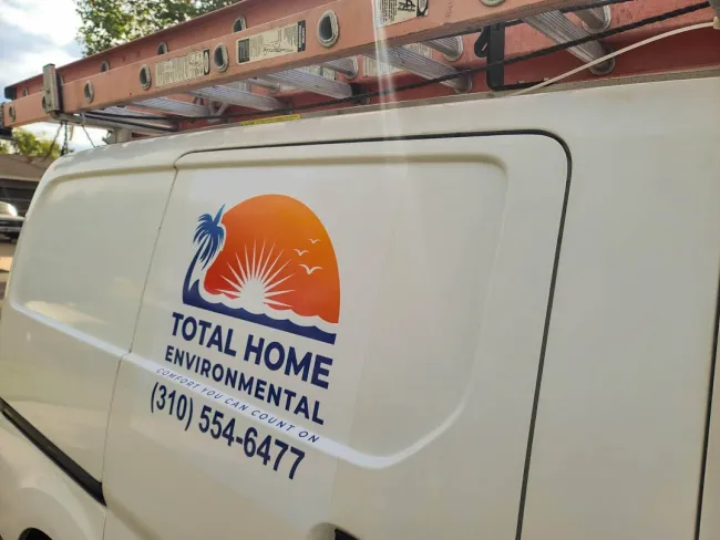 White service van with Total Home Environmental logo, sun and palm tree graphic, and contact phone number.