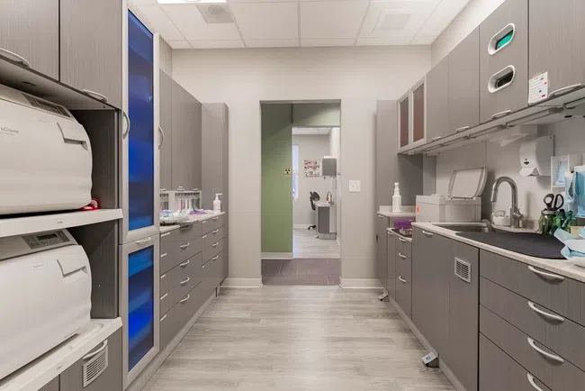 Clean modern medical or dental sterilization room with cabinets, autoclaves, and sink under bright lighting