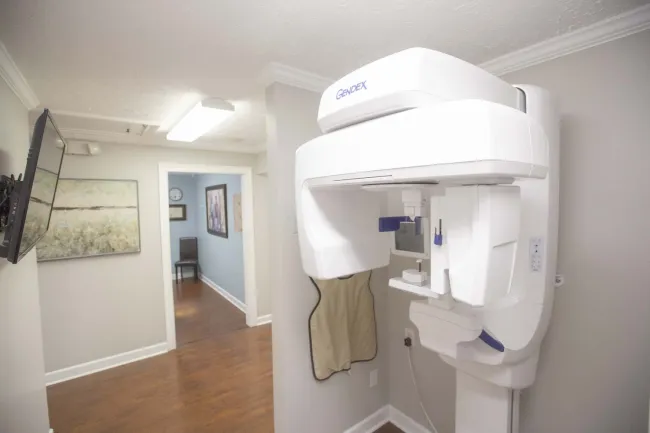 Modern Gendex dental panoramic X-ray machine in a clean, bright dental clinic room with wood flooring.
