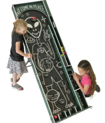 Two girls playing a skee ball game with an alien and peace theme design on the board