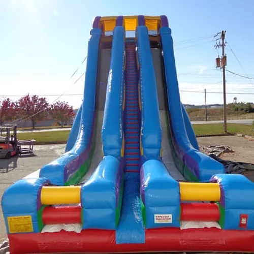 Large colorful inflatable slide with three lanes and a red, yellow, blue, green, and purple design outdoors.