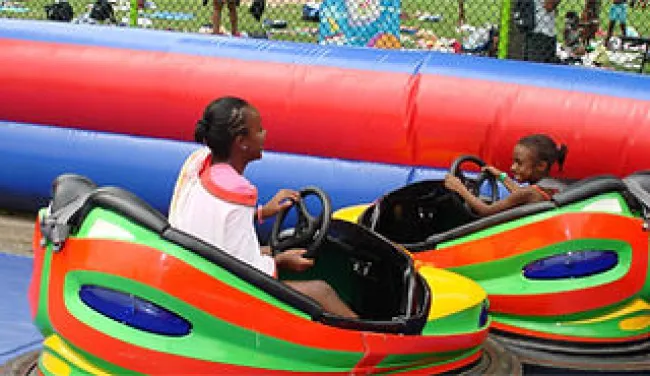 Two children enjoying colorful bumper cars on a sunny day at an amusement park.