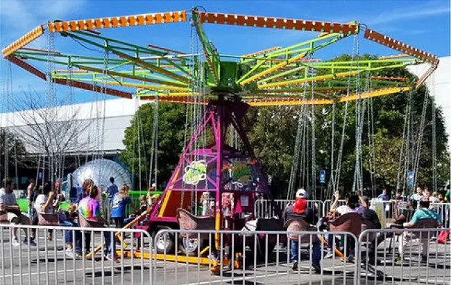 Colorful swing ride at an outdoor carnival with people enjoying seats on a sunny day