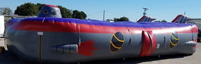 Large inflatable submarine with gray, red, and purple colors displayed outdoors under clear sky.