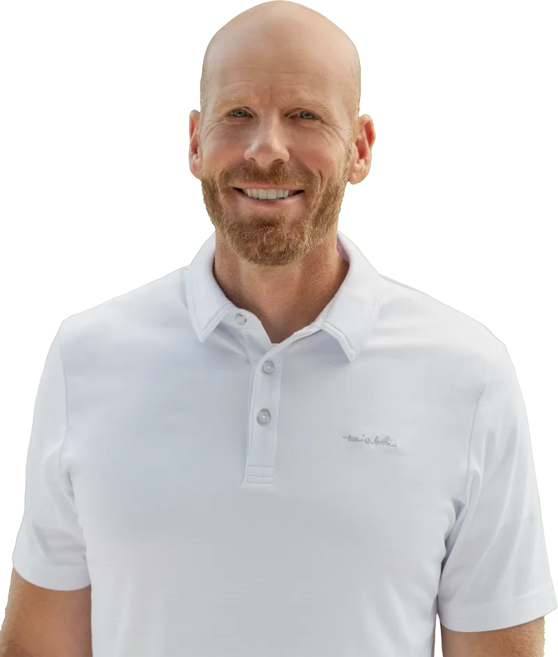 Smiling bald man with ginger beard wearing a white polo shirt with a subtle logo on chest.