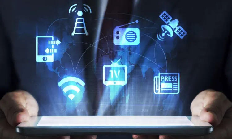 Hands holding a tablet with holographic media icons including WiFi, TV, radio, newspaper, and satellite over a world map.