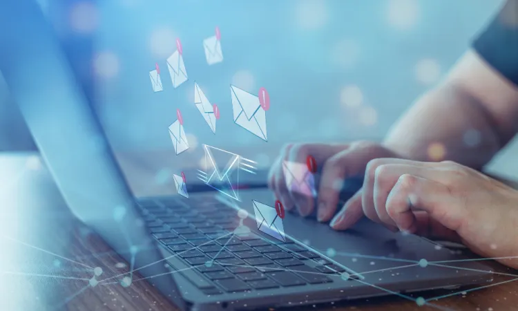 Person typing on laptop with digital envelopes and notification icons representing email communication.