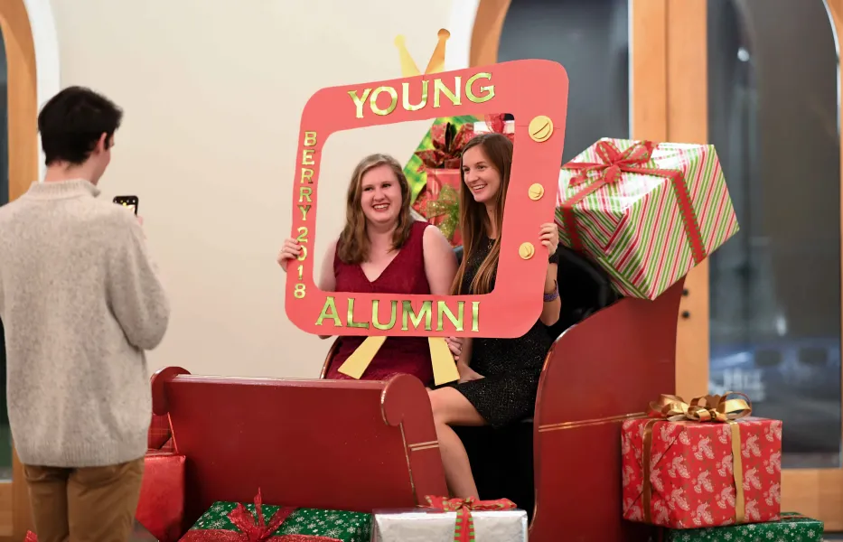 Berry alums post in a sleigh surrounded by Christmas presents