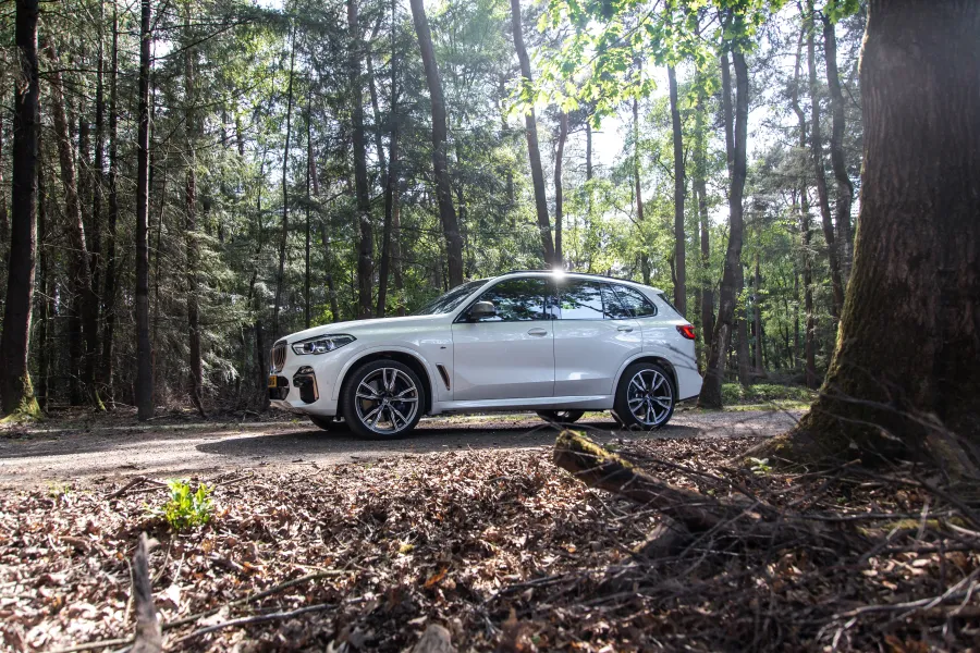 a car parked on pavement near a forest