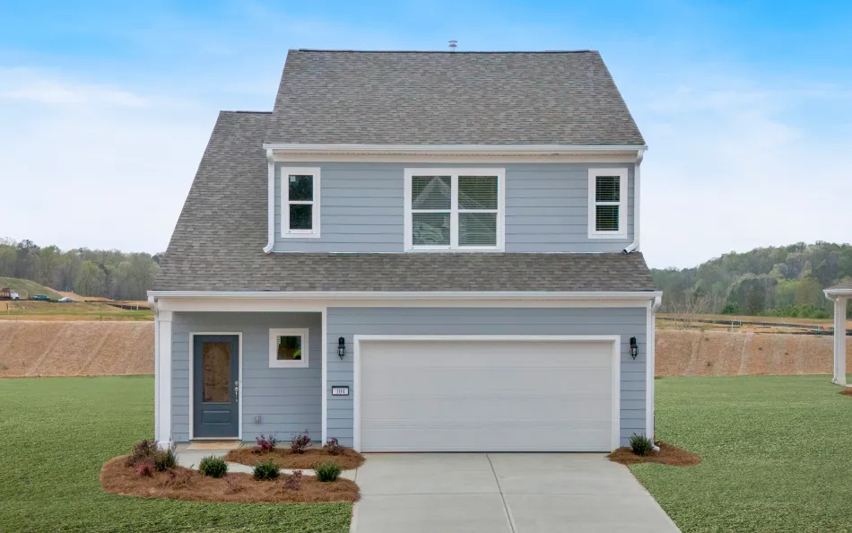 Two-story gray house with a double garage, landscaped front yard, and clear blue sky background