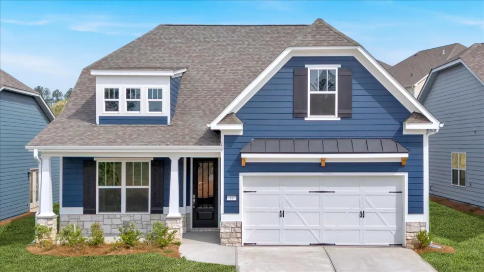 Modern blue house with white trim, stone accents, front porch, and double garage under blue sky.