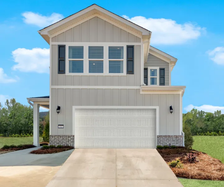 Modern two-story house with white siding, front porch, and spacious driveway under clear blue sky.