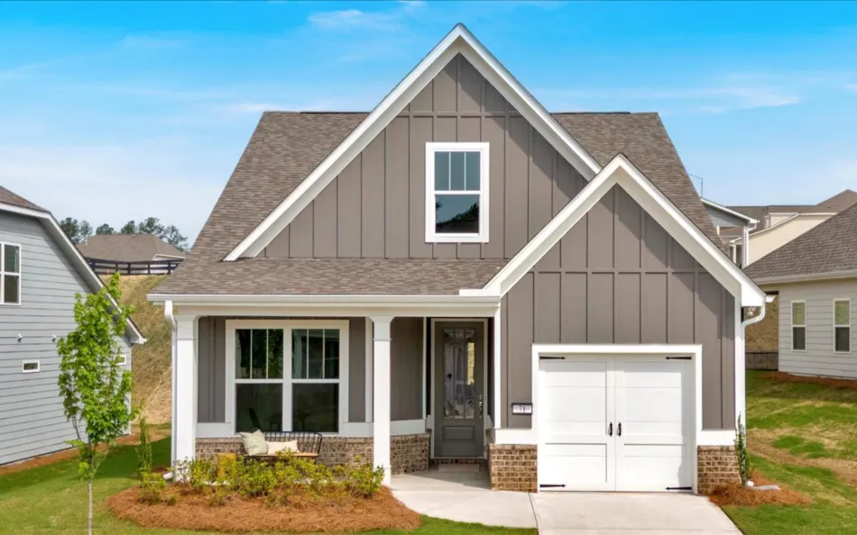 Modern gray house with white trim, landscaped yard, and clear blue sky, showcasing attractive architecture.