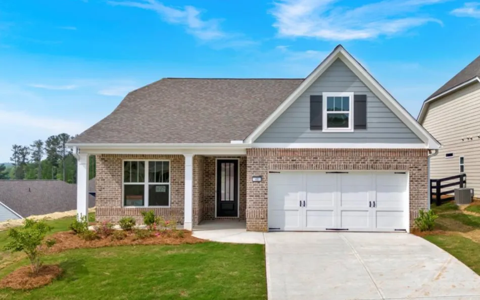 Modern single-story brick house with a two-car garage, front porch, and landscaped lawn under a blue sky.