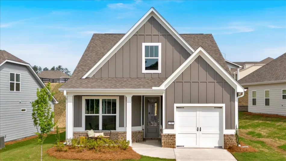 Modern single-family home with gray siding, white trim, porch, garage, and manicured lawn under blue sky