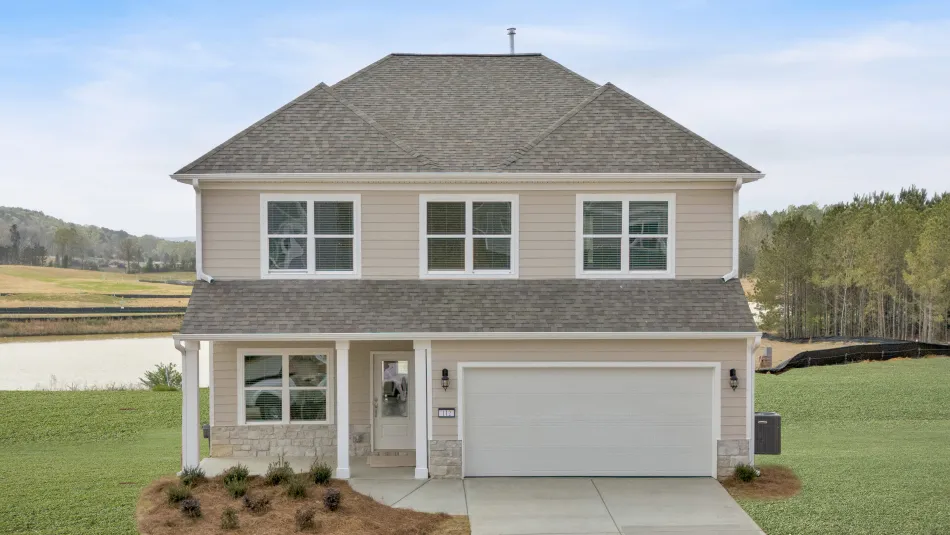 Modern two-story house with white siding, lit windows, and landscaped front yard at dusk.