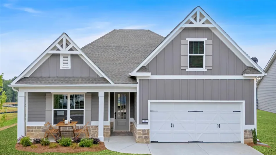 Modern gray house with white trim, stone accents, front porch seating, and a two-car garage on a clear day