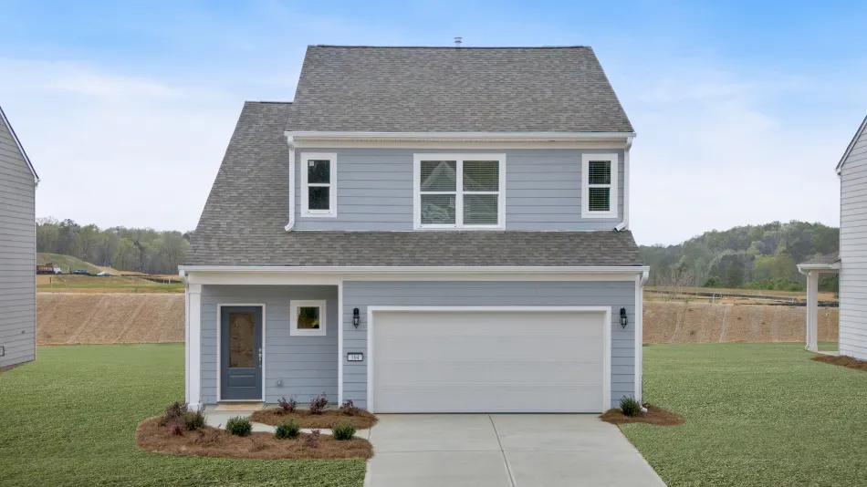Modern gray house with white trim, front lawn, and clear blue sky in the background.
