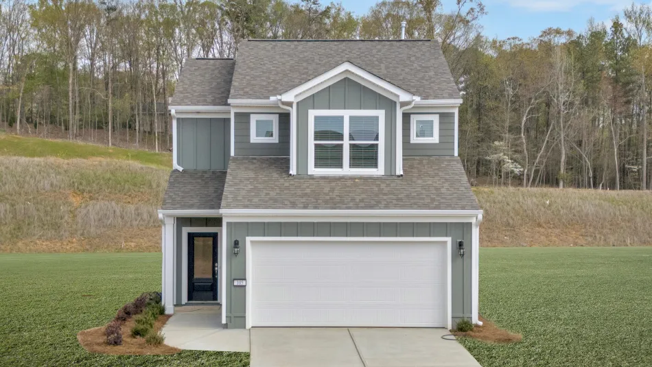Front view of a modern two-story house with a driveway and green landscaped yard.