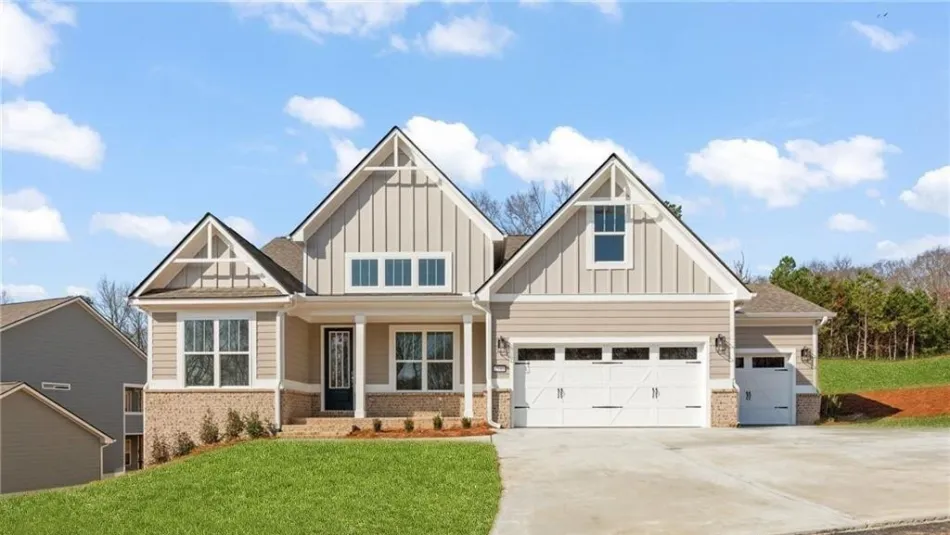 Modern single-story beige house with white trim, double garage, large driveway, and manicured lawn under blue sky