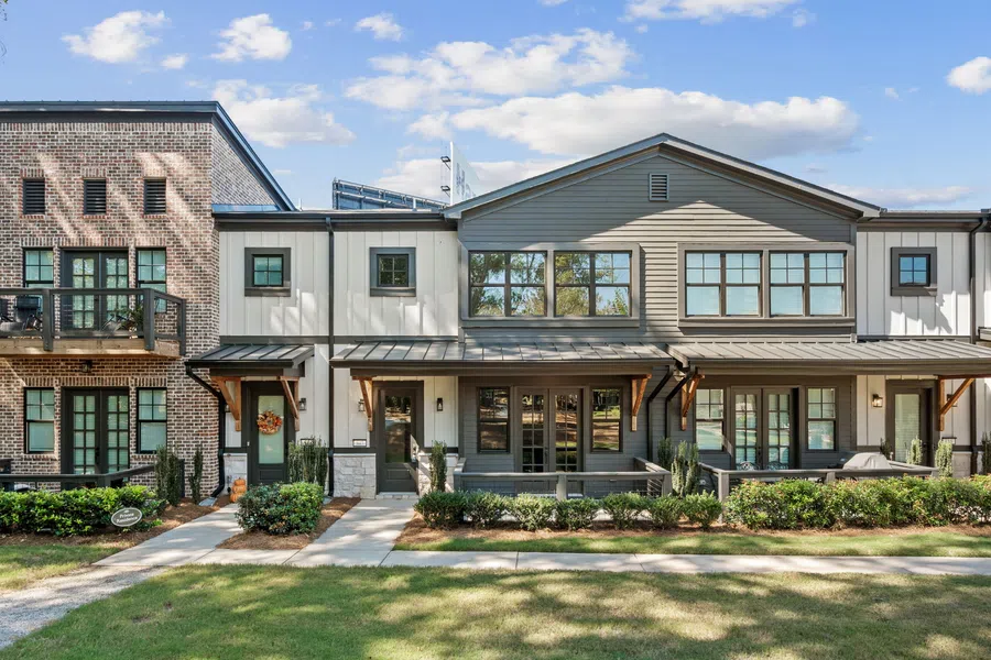 Modern townhouses with mixed brick and siding exteriors under a blue sky and manicured front lawns.