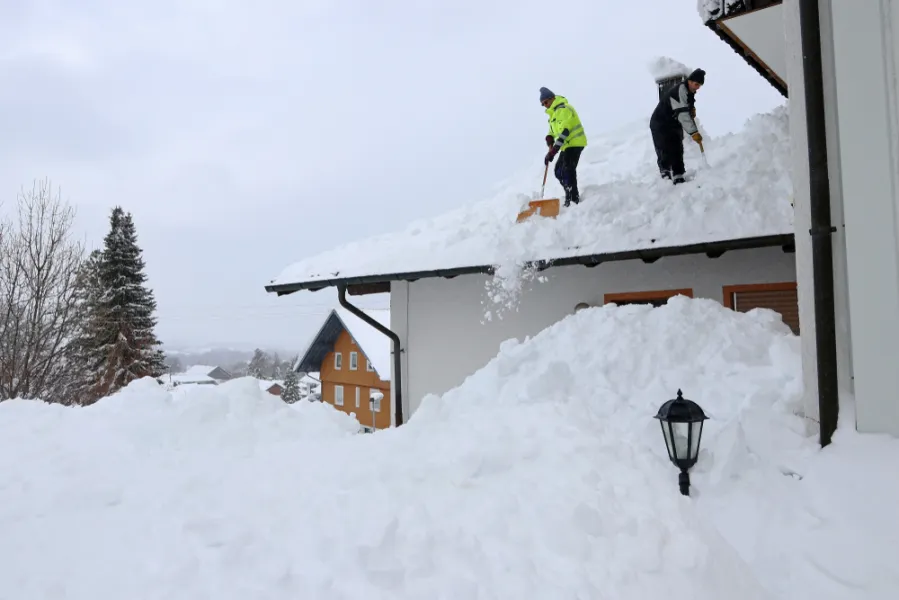 Two People Removing Snow and Ice from Roof
