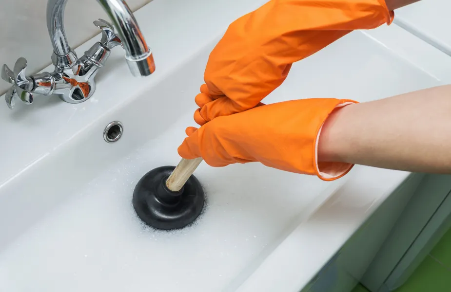 a person's hand holding a small metal object in a sink
