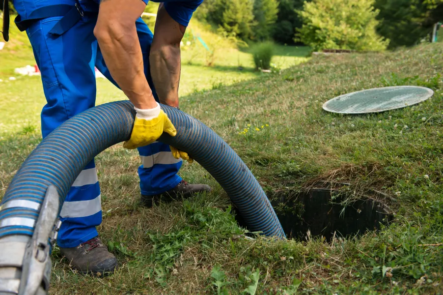 a person using a hose to water a hole in the ground