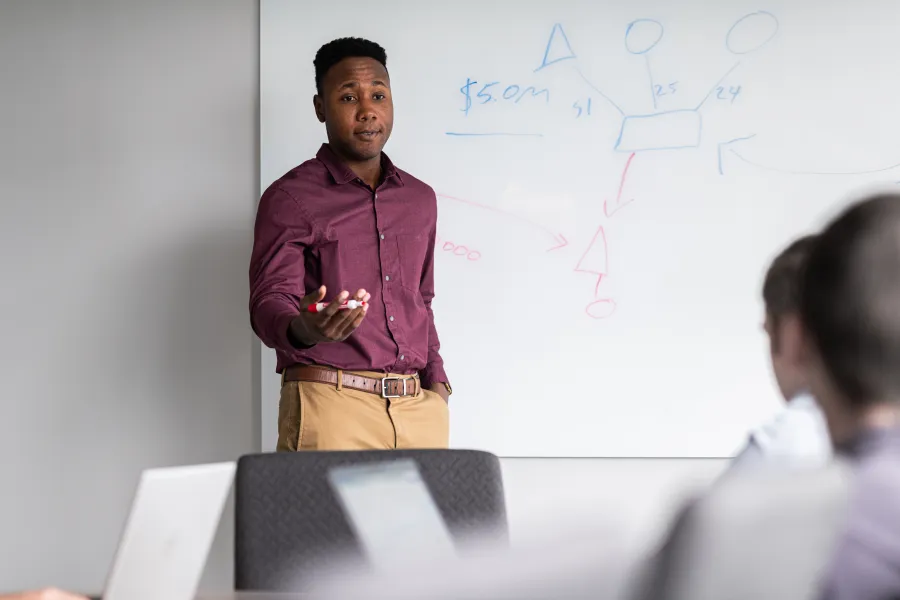 man at a white board presenting