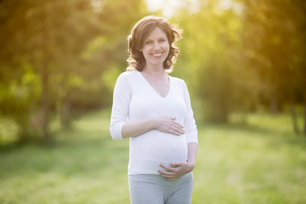 Smiling pregnant woman holding belly