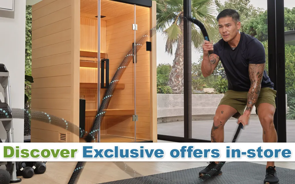 Man exercising with battle ropes in a bright home gym next to a wooden sauna with glass door and outdoor view.