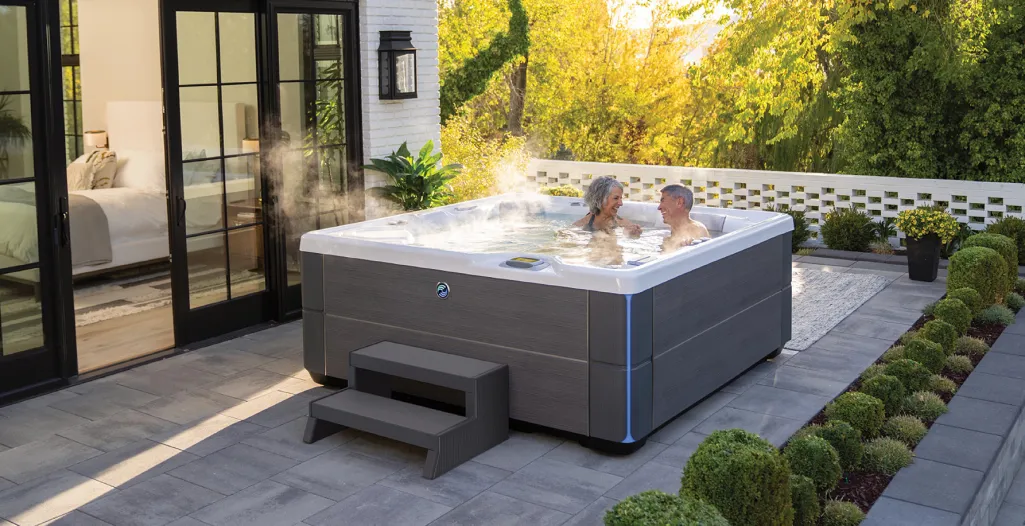 Couple enjoying a steaming hot tub on a modern patio with greenery and outdoor decor