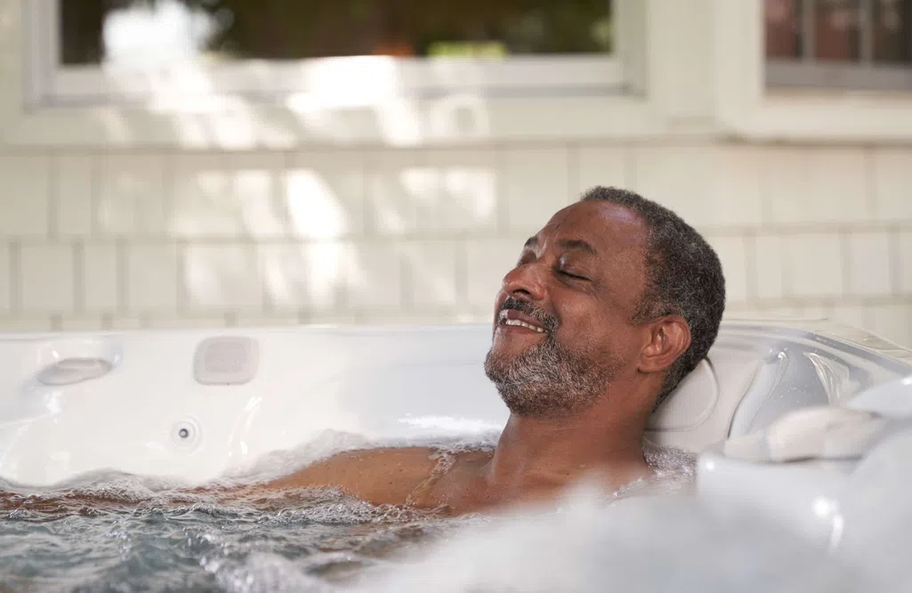 Man relaxing contentedly in a bubbling hot tub with eyes closed and slight smile indoors