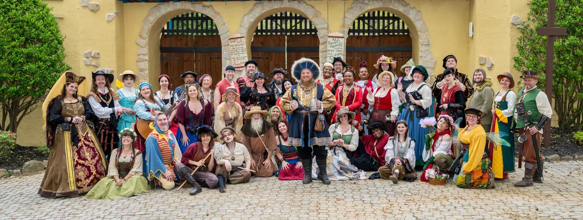 Georgia Renaissance Festival cast members in costume gathered in front of the Festival gate.