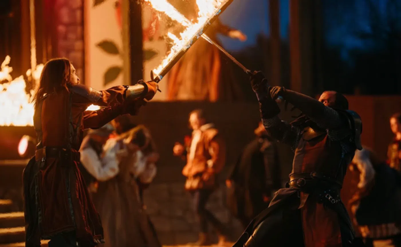Nottingham combatants in a fire-lit sword fight at the tournament field