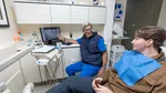 Dentist explains dental X-ray results to a seated male patient in a modern dental office.